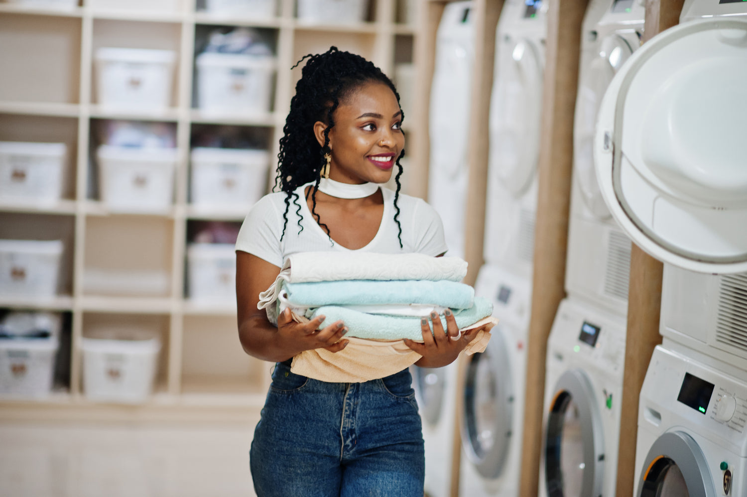Woman holding folded laundry in a laundromat