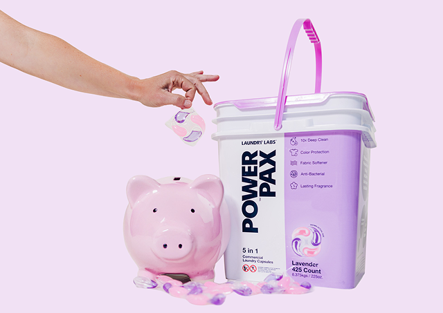 Person holding a Power Pax container next to a pink piggy bank on a light purple background
