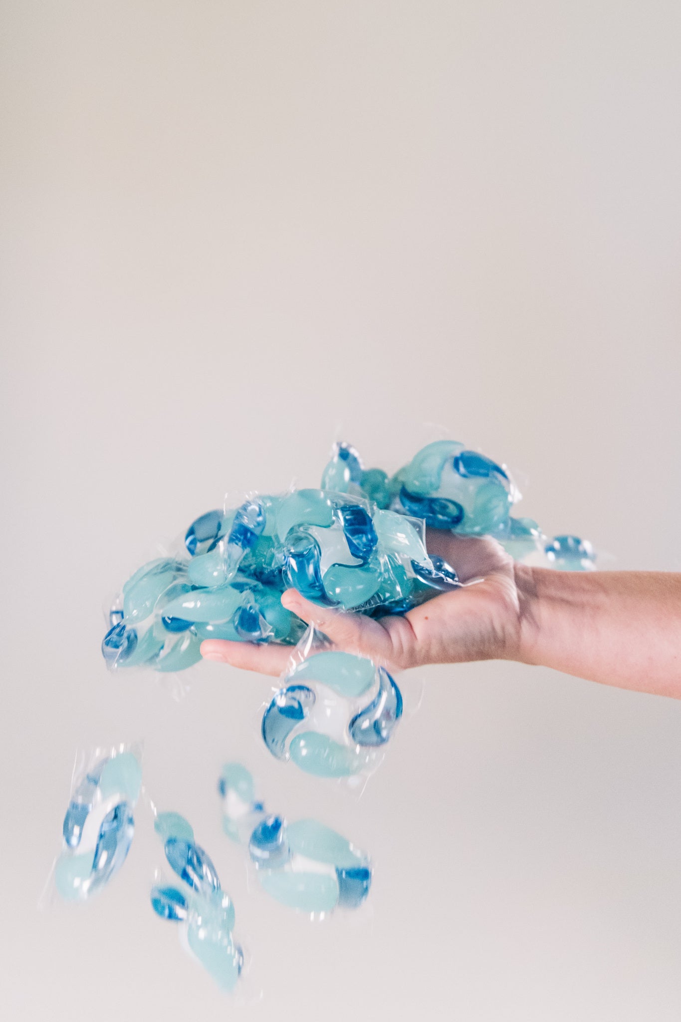 Hand holding a cluster of blue and white marbled objects against a plain background